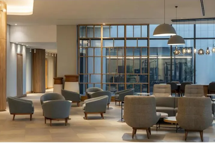 Hotel lounge with upholstered armchairs and a timber-framed glass screen